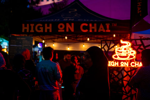 Neon sign and branding for 'High on Chai' at a nighttime event.