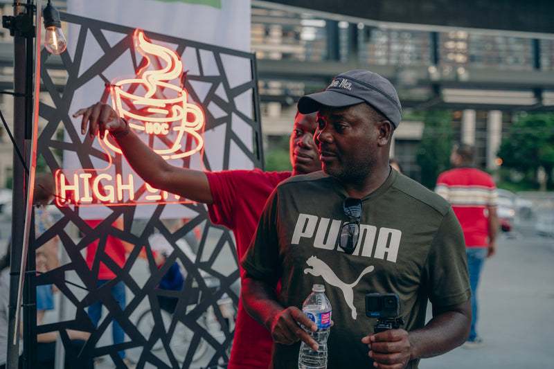 Man in a Puma shirt holding a water bottle with a neon sign in the background