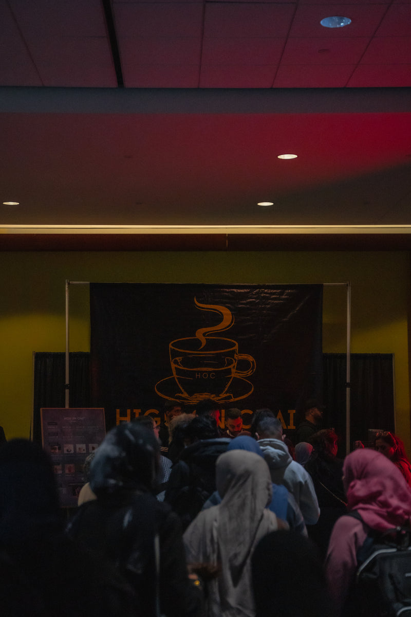 People gathered in a dark room with a Chai-themed poster on the wall.